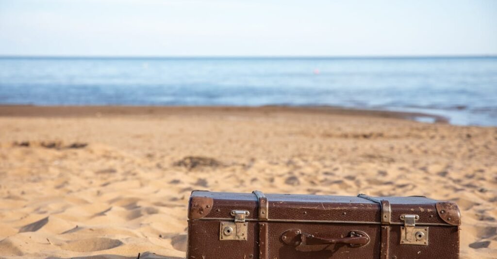 A vintage brown suitcase sits on a sandy beach, evoking travel and adventure.